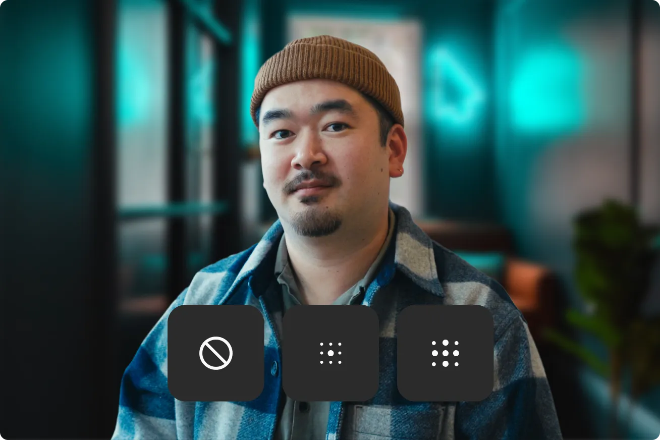 Man wearing a brown beanie and checkered jacket sitting indoors with three dark square icons below him featuring a no entry symbol and two sets of dots.